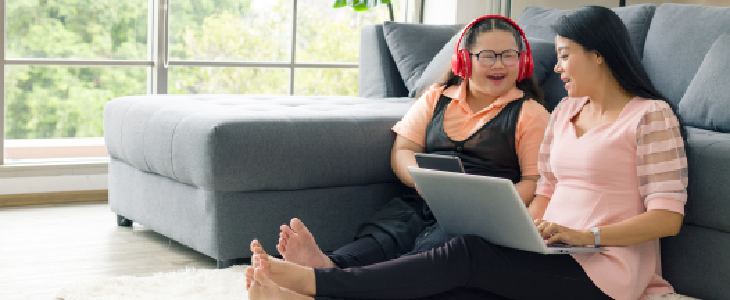 mom and special needs daughter sitting on floor looking at laptop smiling special needs planning